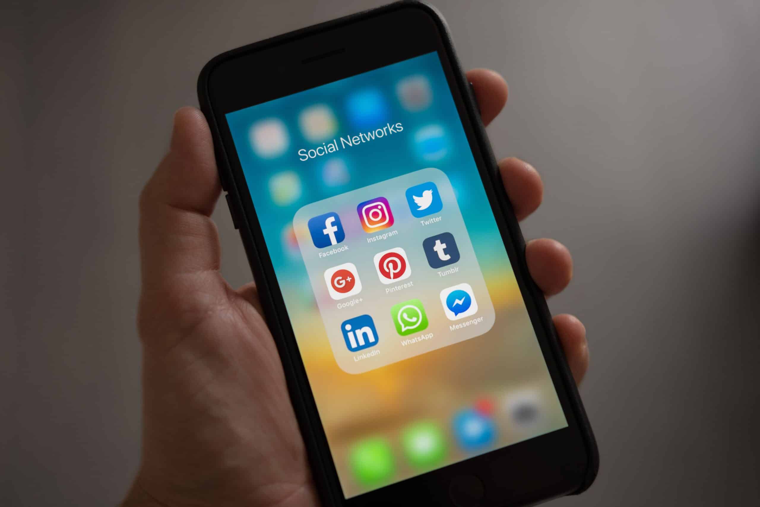 Person holding a smartphone in hand, showing social media apps