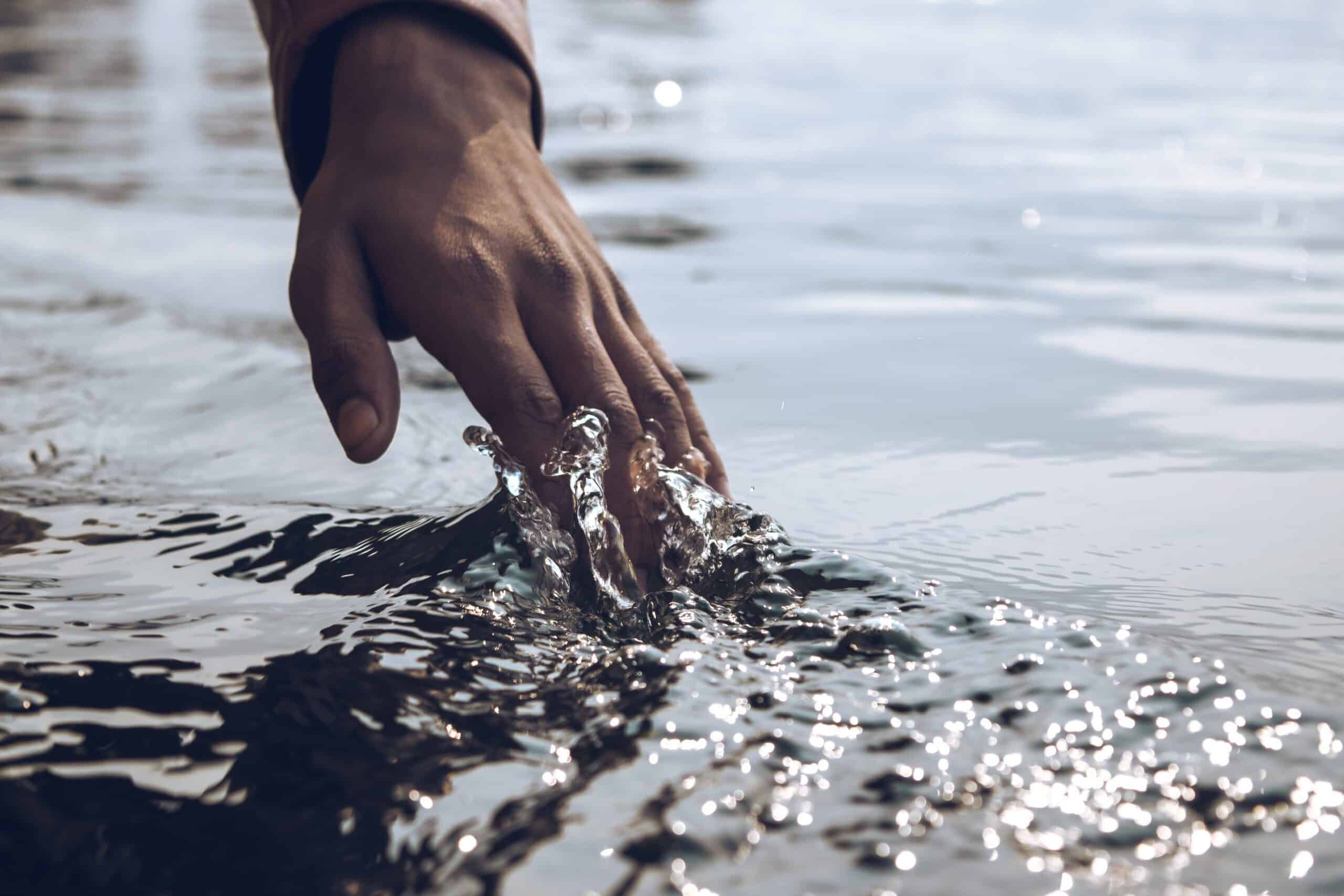 Hand, die das Wasser berührt
