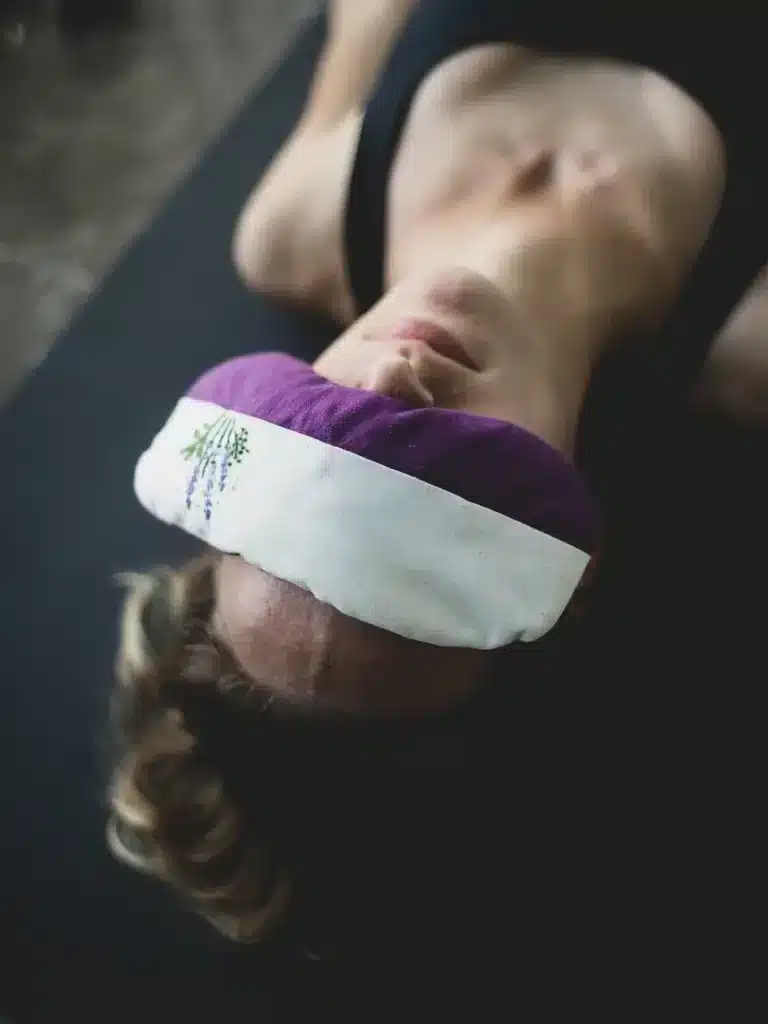 Person in Savasana, Entspannungshaltung, mit Augenkissen