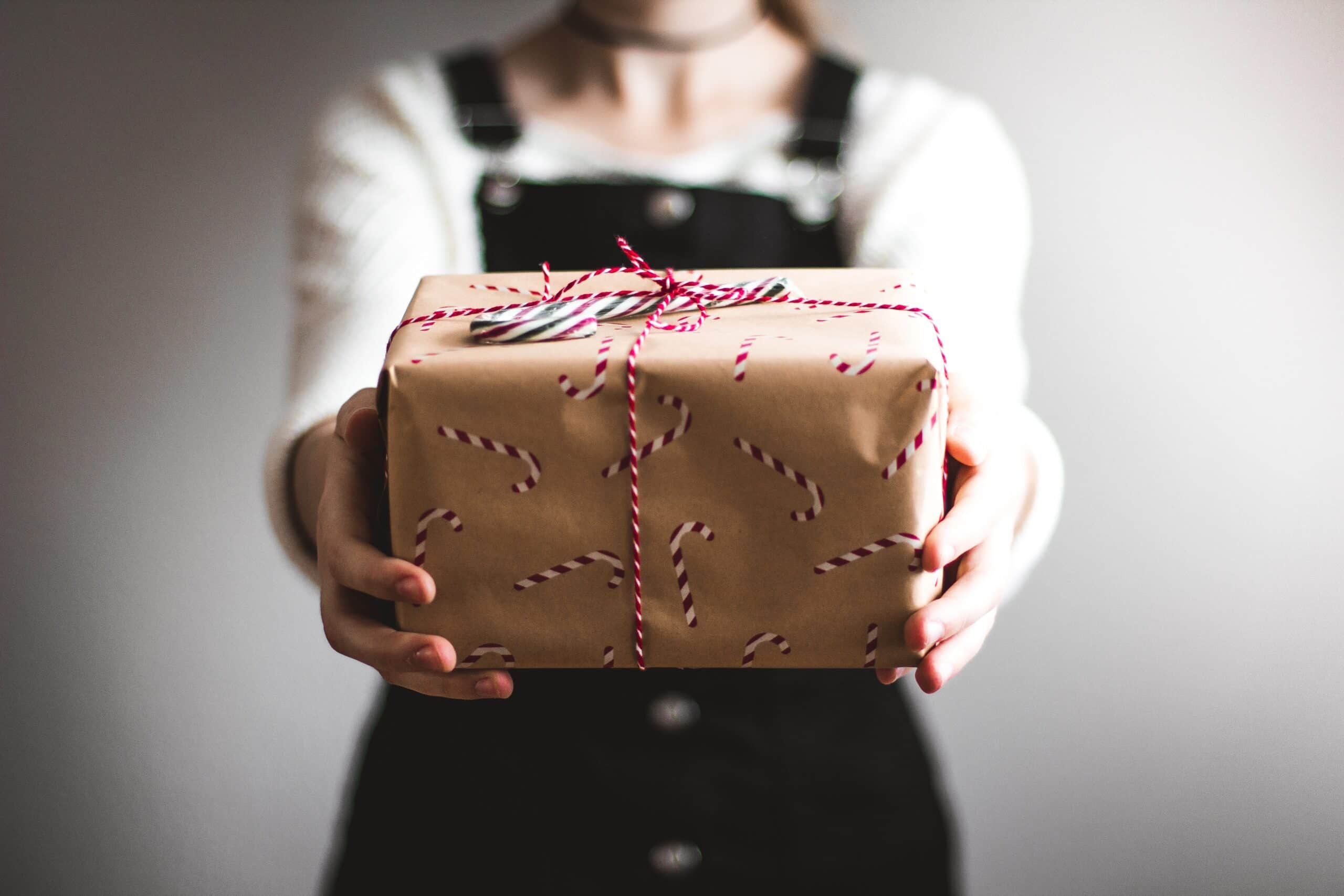Eine Person, die ein Geschenk zur Kamera streckt