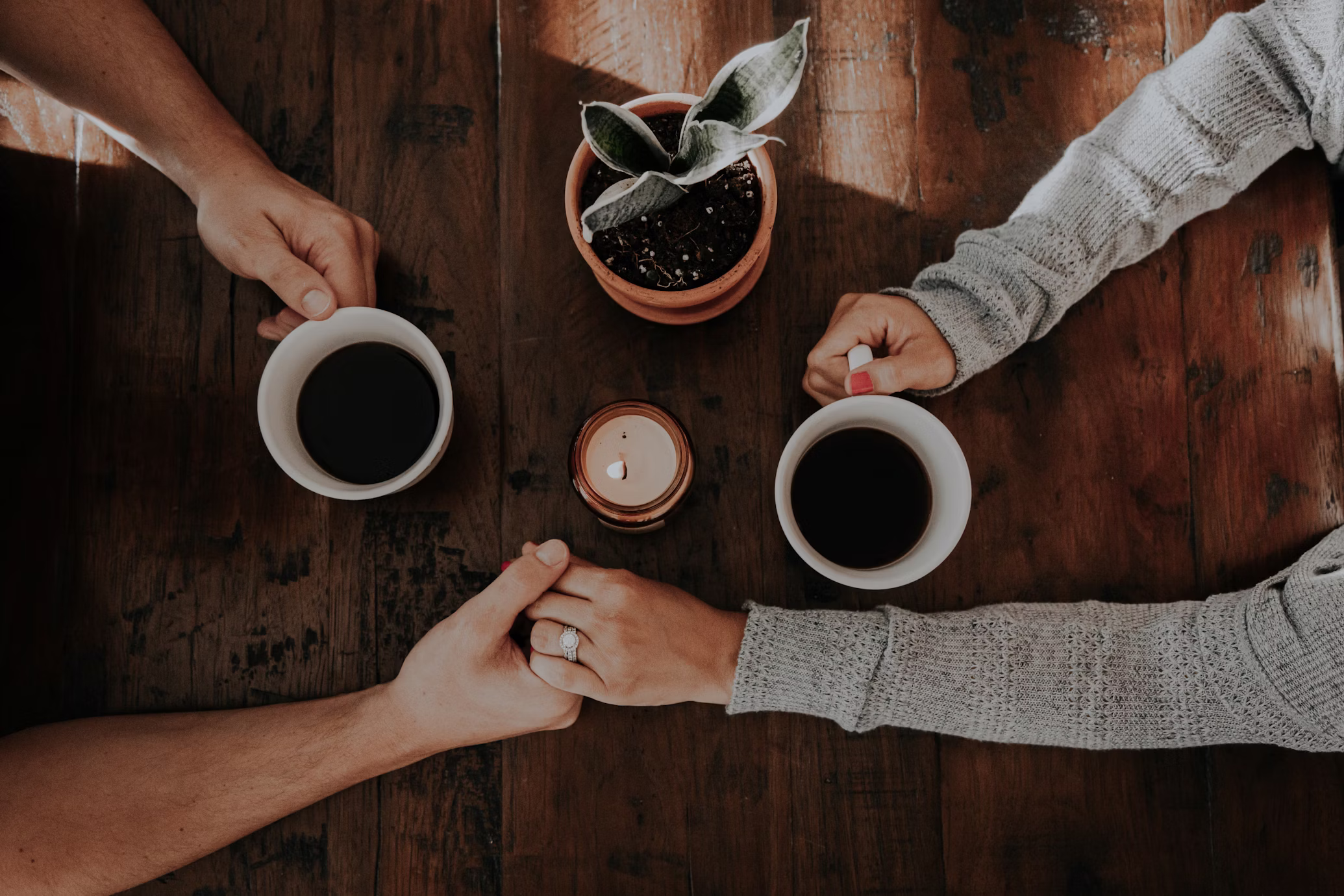 2i Menschen, die sich bei einem Kaffee die Hand halten