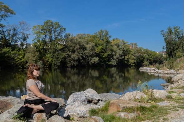 Eine Frau, die am Fluss Yoga macht
