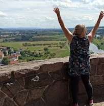 Eine Frau, die vor einer Mauer die Arme in die Luft streckt