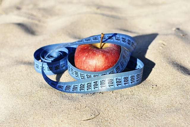 Ein Apfel am Strand, um den ein Maßband liegt