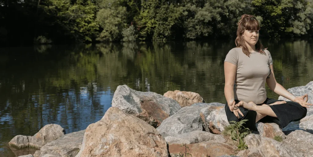 Eine Frau, die an einem Fluss meditiert