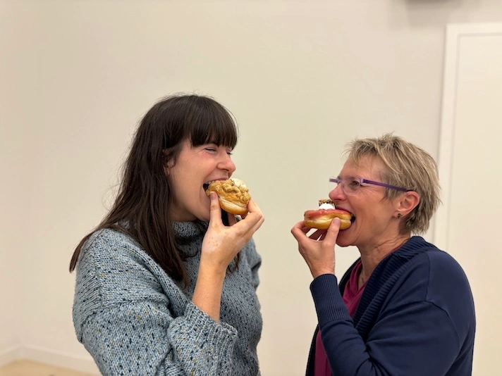 Zwei Frauen, die in einen Donut beißen