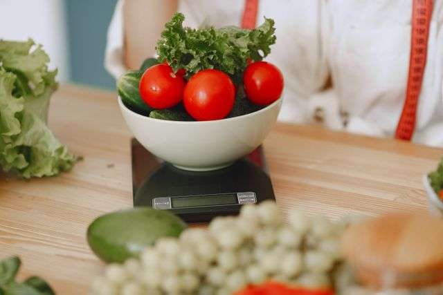 Eine Schüssel mit Tomaten und Grünkohl auf einer Waage